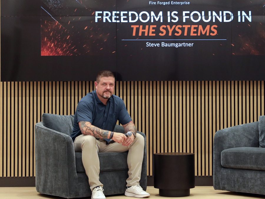 Steve Baumgartner on stage under a slide reading Freedom is found in the systems